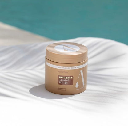 Jar of shimmering tanning butter on a white surface with a blue background