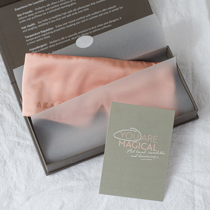 Blush Pink AKA Sleep Deep Sleep Eye Mask is lying in tissue paper in a gift ready charcoal gift box. There is a A5 light grey green card  propped in front of the box with the words "you are magical" written in all caps in light pink. In white script the words "And loved, incredible and deserving x" are underneath. The word YOU is circles in white to emphasize it.